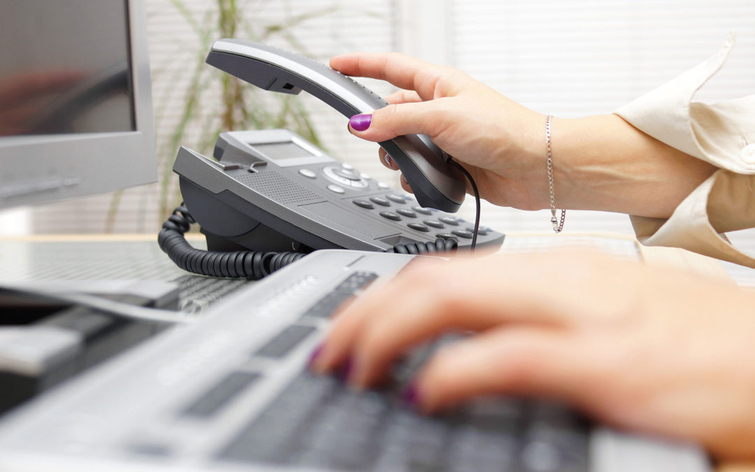 woman using computer and desk phone