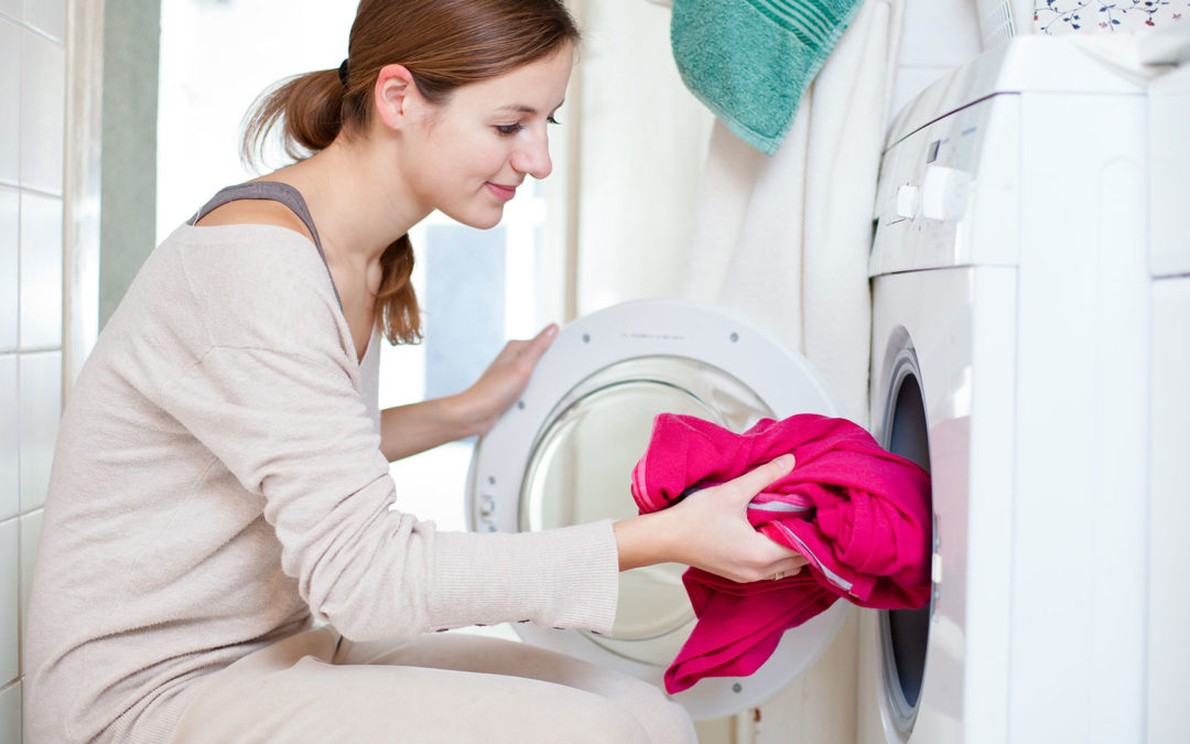 woman putting clothing in washing machine