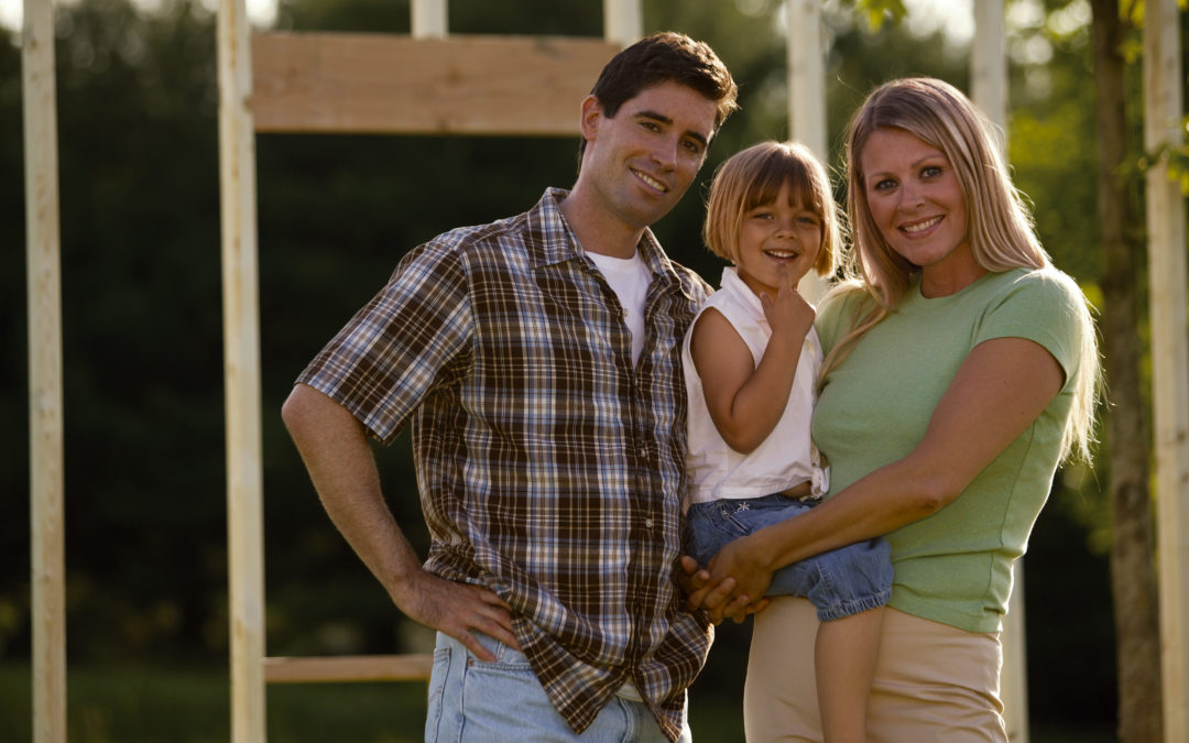 Family outside framed house